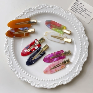 Set of 8 colorful acetate hair clips in amber and marble patterns on a white plate