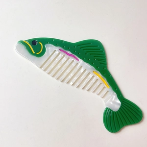 Détail d'un peigne en acétate en forme de poisson avec fini nacré et dents larges