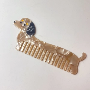 Detail d'un peigne en acetate en forme de teckel avec texture marbree et dents larges