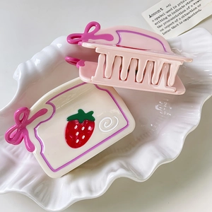 Lot de pinces à cheveux rose et motif fraise dans un plateau décoratif en coquillage