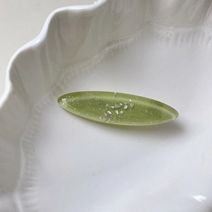 Macro detail of oval shell hair clip with translucent green resin and glitter flakes