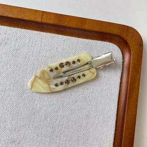 Detailed close-up of marble yellow acetate hair clip with brown rhinestone accents