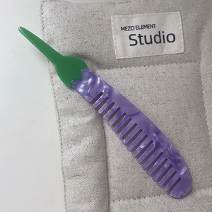 Macro detail of eggplant shaped acetate hair comb with purple marble texture and green handle