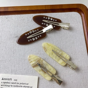 Set of 4 acetate hair clips with rhinestones and marble patterns on a display board
