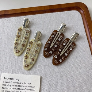 Detailed view of four acetate hair clips with inlaid rhinestones on a display tray