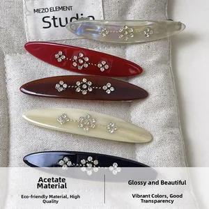 Close-up of five acetate hair clips with sparkling rhinestone flower motifs