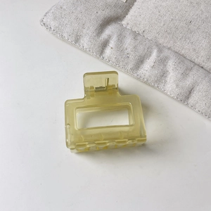 Close-up of a large yellow translucent square claw clip with hollow geometric design
