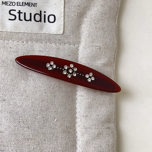Detail view of oval hair clip with sparkling flower rhinestones on a warm brown base