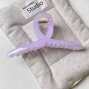 Close-up of lavender translucent jelly claw clip with metal spring on quilted background