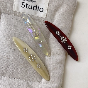 Macro detail of three vintage floral hair clips with sparkling rhinestones on grey fabric