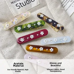Close-up of acetate floral hair clips with rhinestones on a beige canvas background