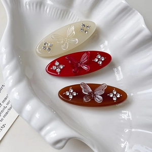Three-piece set of oval butterfly hair clips with crystals in white, red, and amber colors