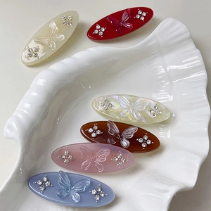 Elegant butterfly oval hair clips with rhinestones in six colors on a white shell tray