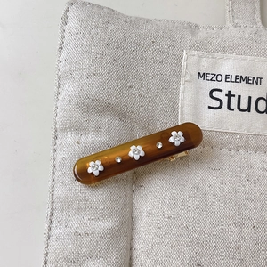 Detail of amber resin hair clip with three white flowers and sparkling rhinestones