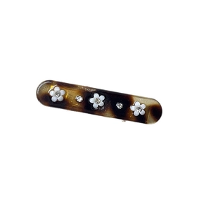 Vintage tortoiseshell hair clip with white floral rhinestones on a white background