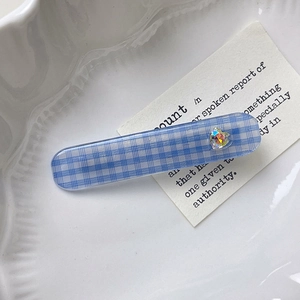 Blau karierte Haarspange mit Herz-Strassstein auf einem dekorativen Porzellanteller