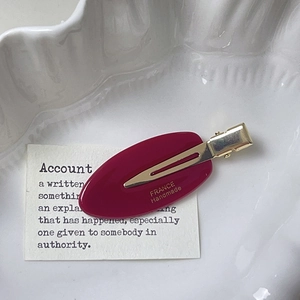 Vue détaillée d'une barrette ovale magenta en acétate avec clip bec de canard doré