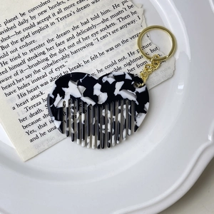 Detail of heart-shaped acetate mini comb keychain with black and white marble texture