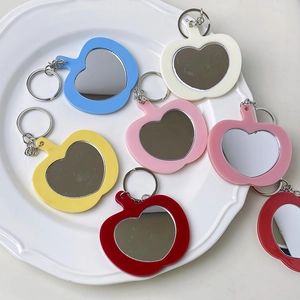 Llaveros de espejo coloridos con forma de corazón y manzana en seis tonos sobre un plato