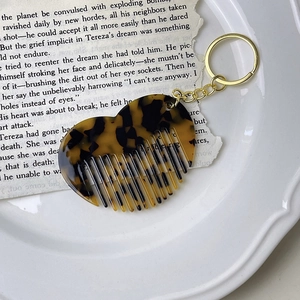 Detailed close-up of tortoise shell acetate heart comb with gold metal keychain hardware