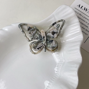 Détail de la pince à cheveux papillon en acétate marbré montrant les ailes ajourées