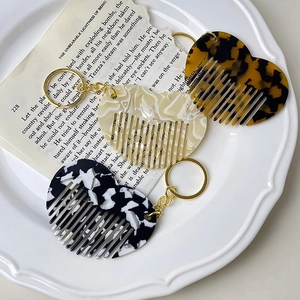 Mini heart-shaped acetate hair comb keychains in marble, ivory, and tortoiseshell patterns