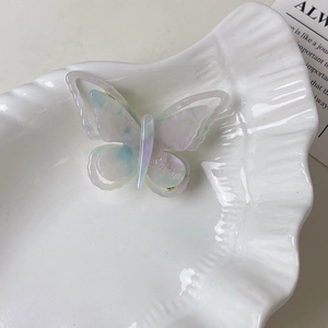 Détail d'une pince à cheveux papillon en acétate irisé avec gravure SIM élégante