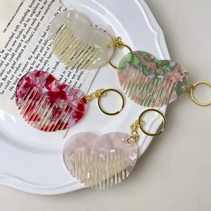 Mini heart-shaped acetate hair comb keychains in four colorful marble patterns