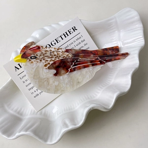 Detailed view of swallow hair claw in marbled acetate resting on a decorative shell plate