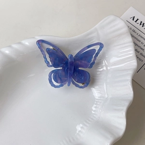 Vue détaillée de la pince à cheveux papillon colorée avec texture marbrée et logo SAN