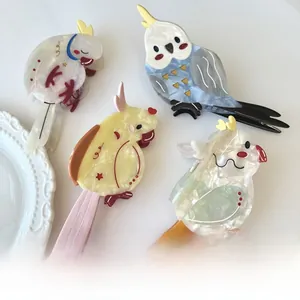 Macro detail of bird-shaped acetate hair claws with marble texture in four soft colors