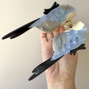 Detail of bird-shaped acetate hair claw clip featuring blue and white marble textures