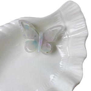 Pince à cheveux papillon en acétate irisé avec dégradé bleu-violet nacré sur plateau coquillage