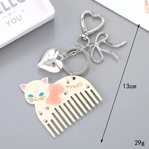 Détail d'un peigne chat en acétate avec nœud rose et pendentif en forme de cœur argenté