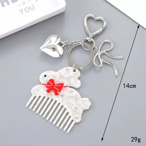 Détail macro d'un porte-clés peigne lapin en acétate blanc avec nœud rouge et cœurs
