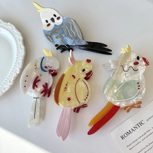 Chic parrot-shaped acetate hair claws in various marble colors on a decorative tray