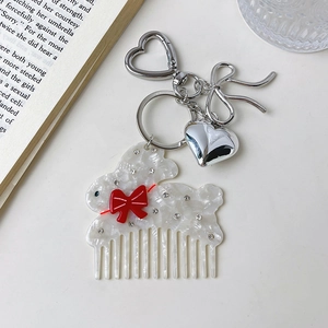 Détail d'un porte-clés peigne lapin en acétate avec nœud rouge et pendentif cœur