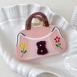 Detail of pink handbag-shaped hair claw with brown bear and colorful flower patterns