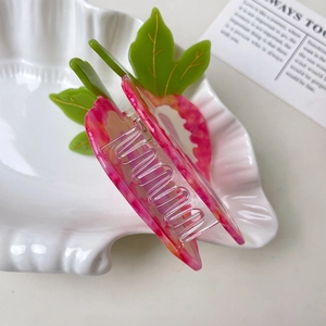 Detail of strawberry heart claw clip made of pink acetate with green leaf design