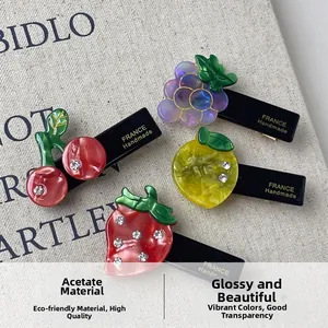 Detailed close-up of fruit-themed acetate hair clips with sparkling rhinestone accents