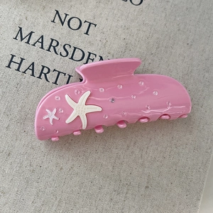 Close-up of pink starfish hair claw with sparkling rhinestones on canvas background