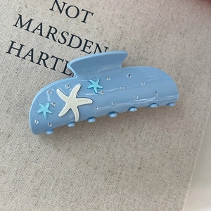 Close-up of a blue starfish hair claw clip with rhinestones on a textured background