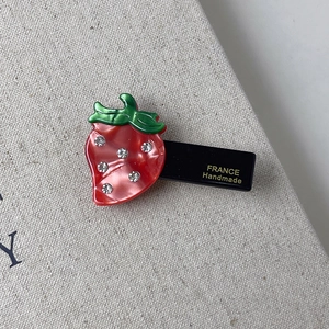 Detailed macro view of a cute strawberry hair clip with rhinestones and handmade marking
