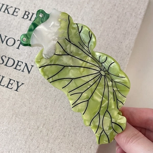 Détail d'une pince à cheveux en acétate vert émeraude et blanc avec motifs de nervures