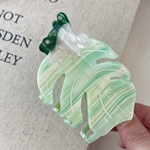 Vue macro d'une pince à cheveux feuille marbrée verte ornée de strass et dents antidérapantes
