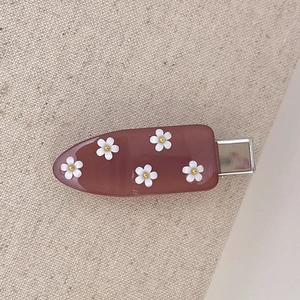 Dettaglio del fermaglio per capelli in resina rosa con margherite 3D e clip in metallo argento