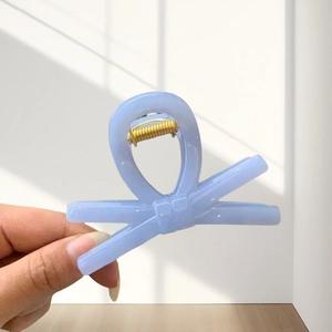 Close-up of lavender bow claw clip with gold spring detail in natural light