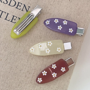Set di quattro fermagli per capelli in acrilico colorato con fiori e dettagli oro