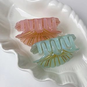 Detail view of shell-shaped hair claws with golden lines and sparkling rhinestones