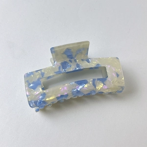 Detail of hollow rectangular claw clip with blue and purple marble texture finish